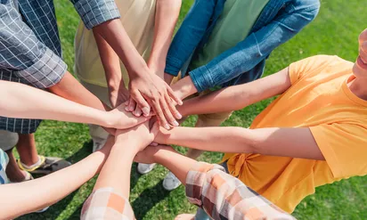 A group of people holding their hands in the center of a circle