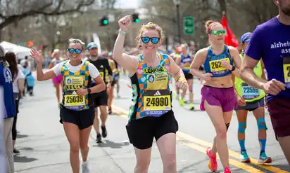 Marathon participants running and smiling at the camera