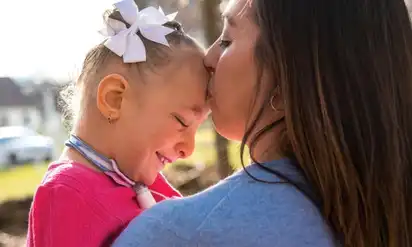 A woman kisses her daughter, Kennedy