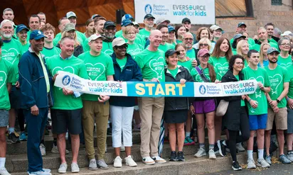 Walk Event sponsors wearing matching green shirts hold a sign for the Eversource Walk for Boston Children's Hospital