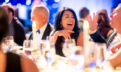 Attendees sit at a table smiling and laughing at the Milagros Event for BCH