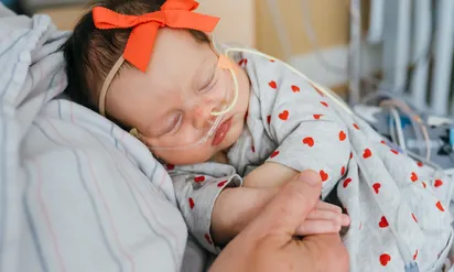 Kalea with a breathing tube being held by her mother