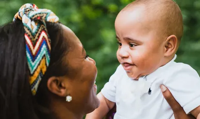 kole smiling and being held up by his mother
