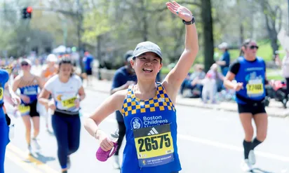 woman running marathon waving at crowd
