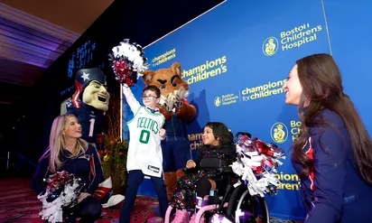 Boy wearing Celtics jersey holding a pompom with cheerleaders and mascot