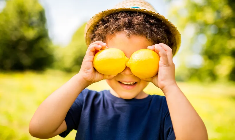 A boy holding two lemons to his eyes