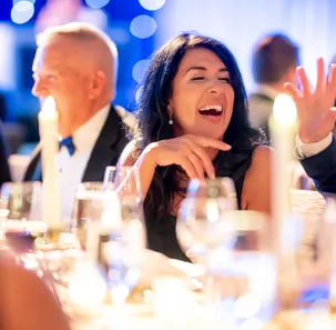 Attendees sit at a table smiling and laughing at the Milagros Event for BCH