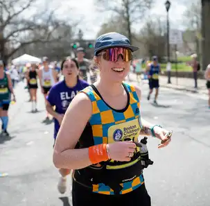 A smiling woman runs at a marathon event for Boston Children's