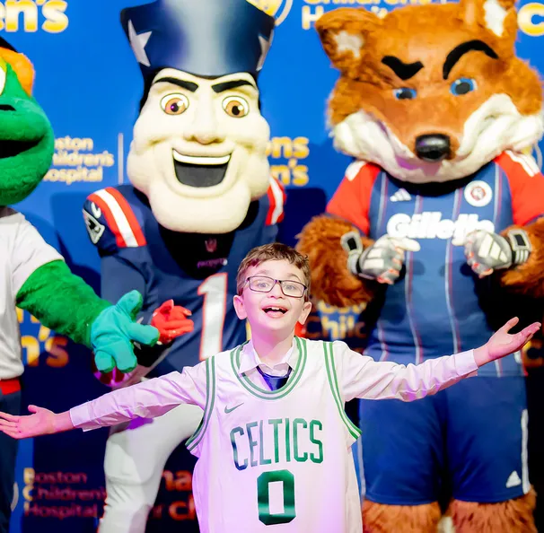 boy in glasses wearing a Celtics jersey in front of mascots