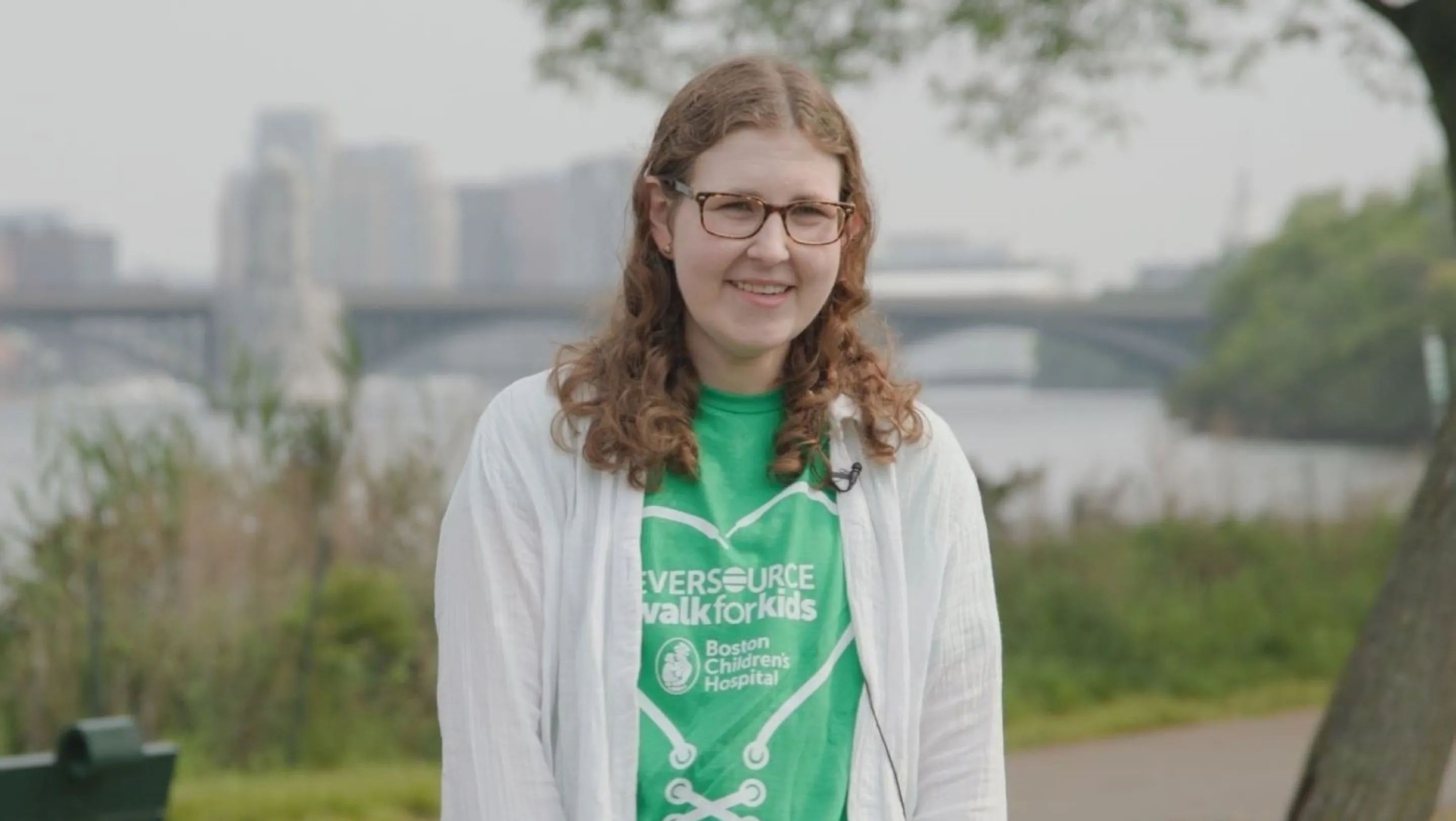 girl with glasses in green shirt standing along the Charles River in Boston