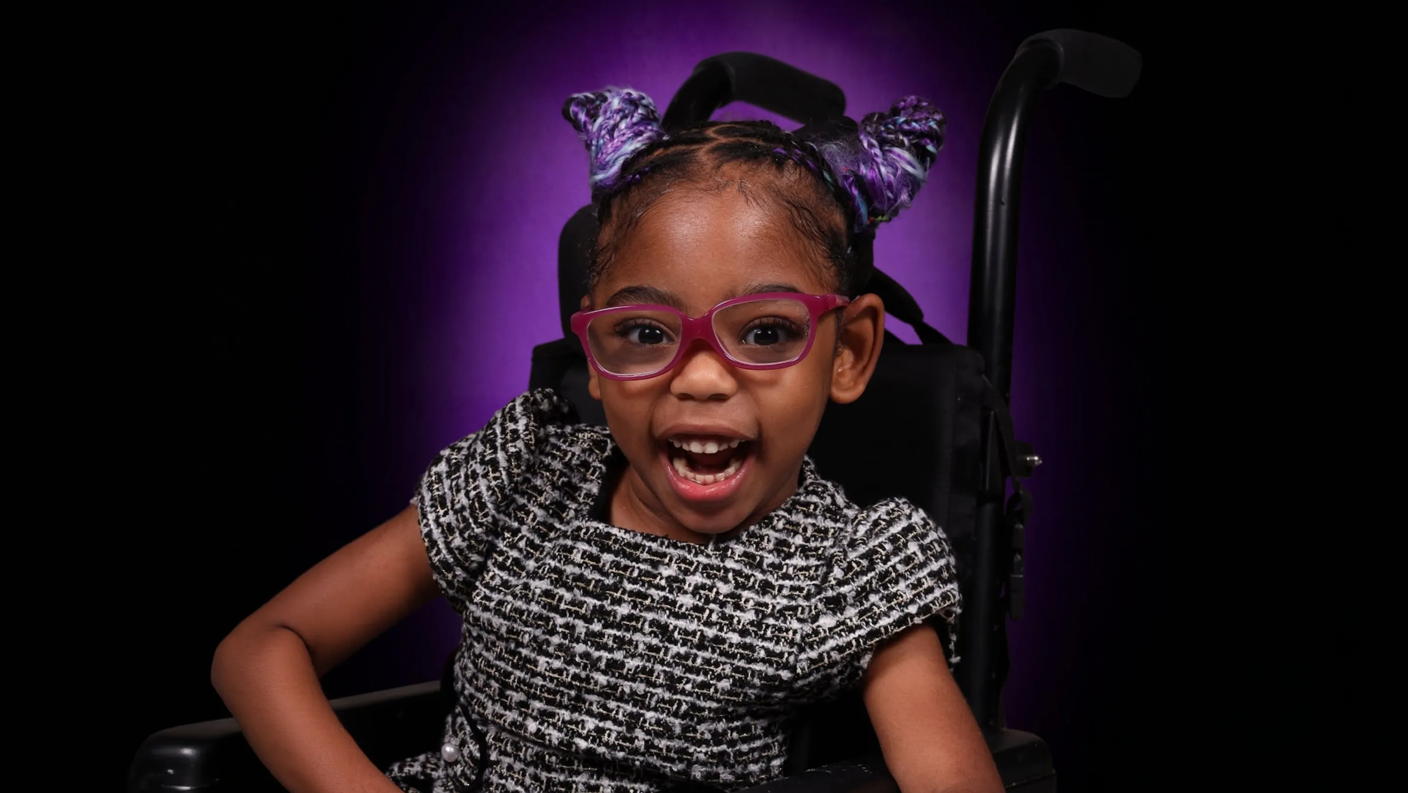 young girl smiling in pink glasses on a wheelchair