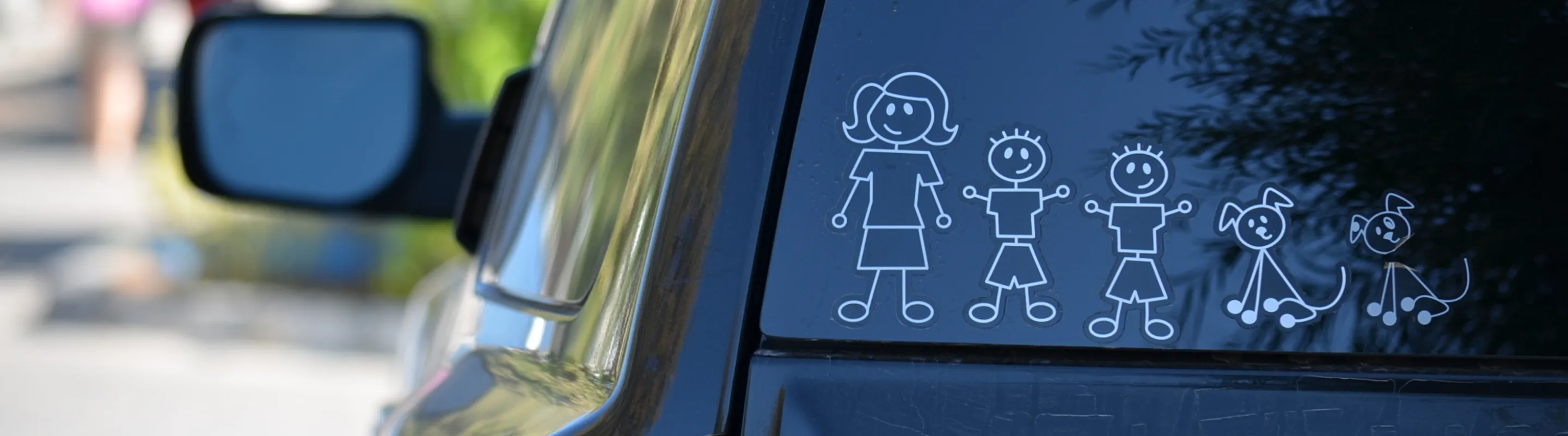 The back windshield of a car that has a set of stickers of a pencil figure family
