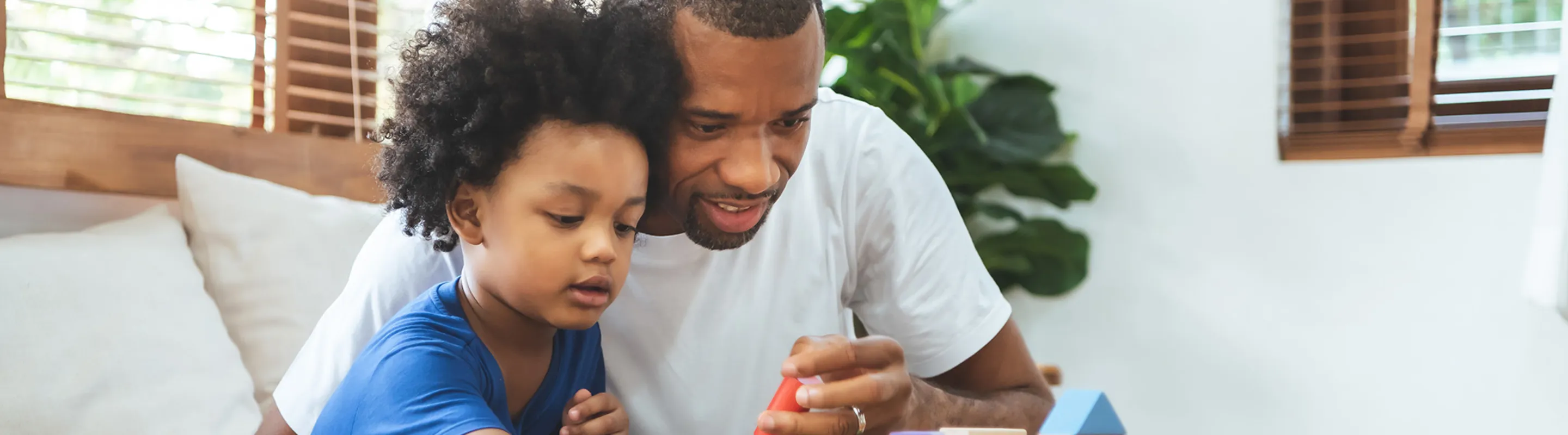 A father and son play with wooden blocks on a table