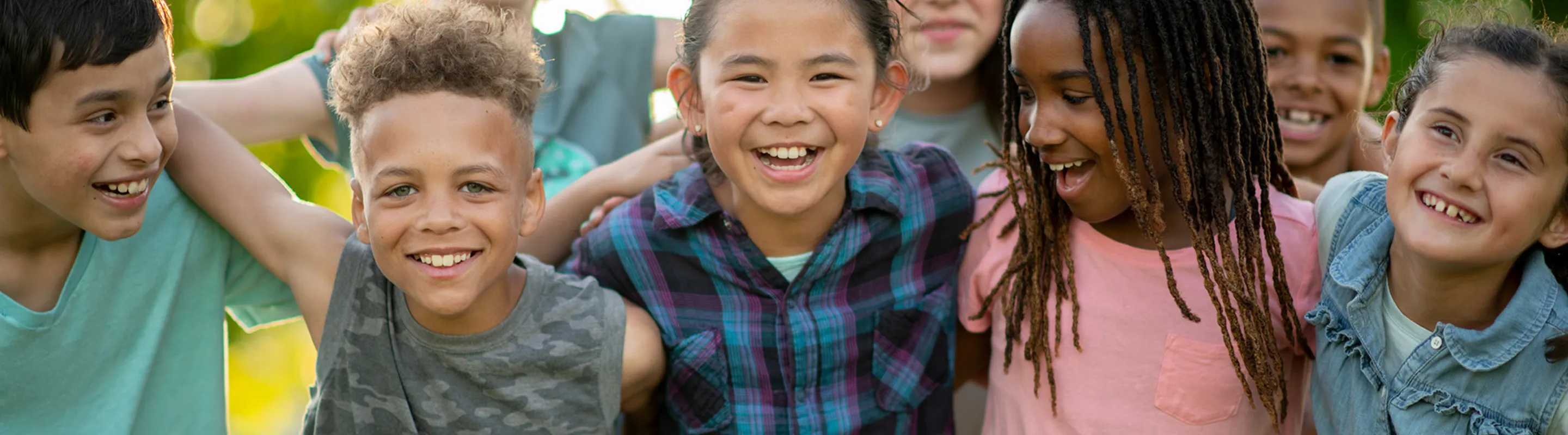 group of children smiling and laughing with their arms around each other
