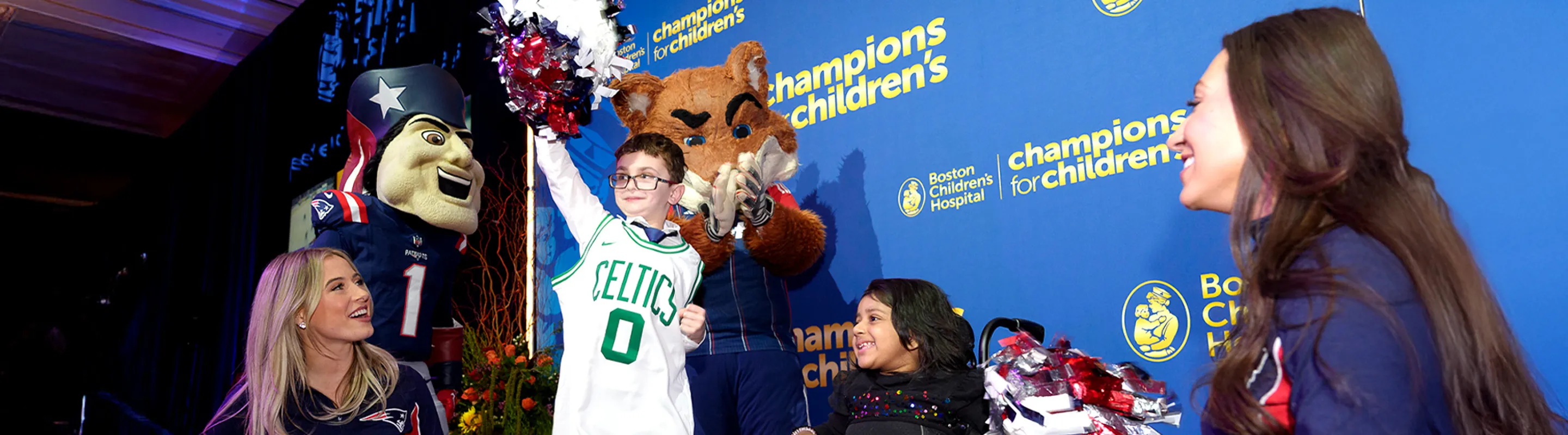 Boy wearing Celtics jersey holding a pompom with cheerleaders and mascot