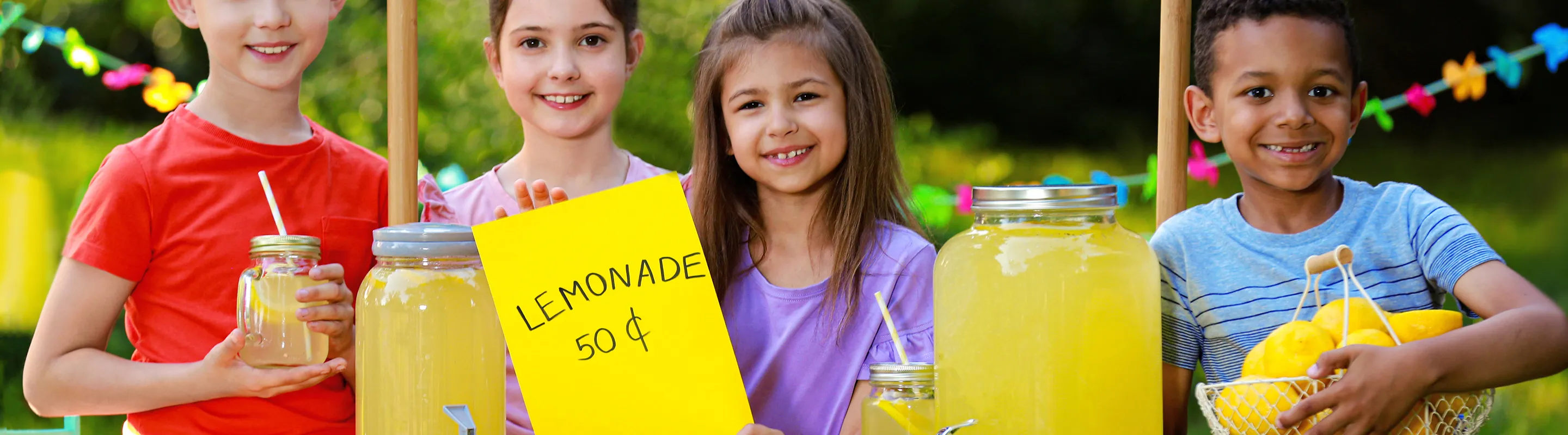 children smiling by a lemonade stand