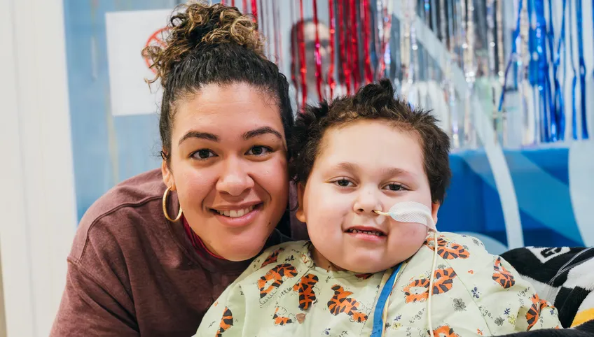 A woman hugs a BCH patient. Both are smiling at the camera