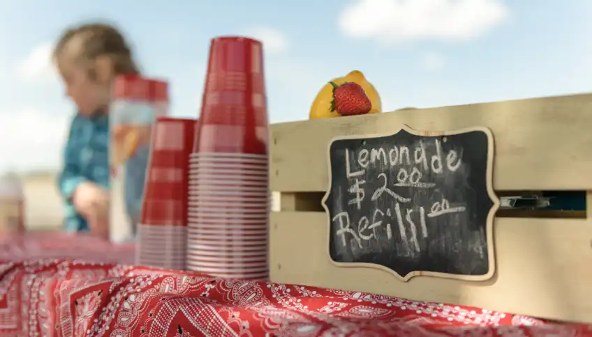 A closeup shot of a lemonade sign and cups at a lemonade stand fundraiser