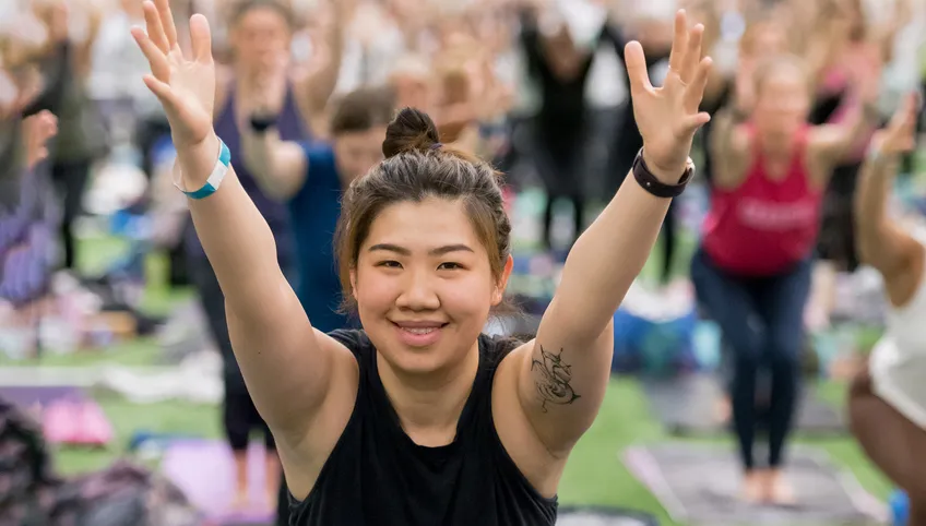 A woman holds her arms in the air as she does yoga at the Yoga Reaches Out event for BCH