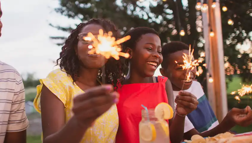 Three kids holding sparklers and laughing