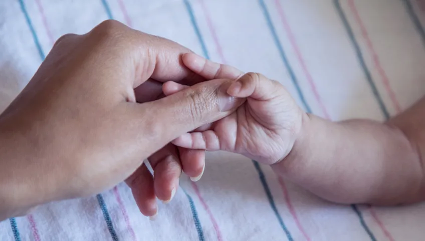 An adult hand holding a baby's hand for Boston Childrens Hospital
