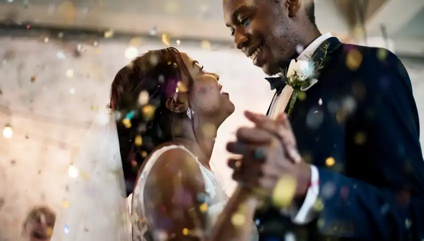 smiling couple dancing on their wedding day, confetti flying in the air