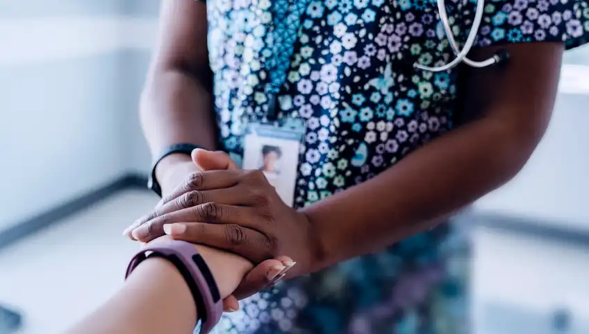 Nurse holds the hand of a patient for Boston Children's Hospital