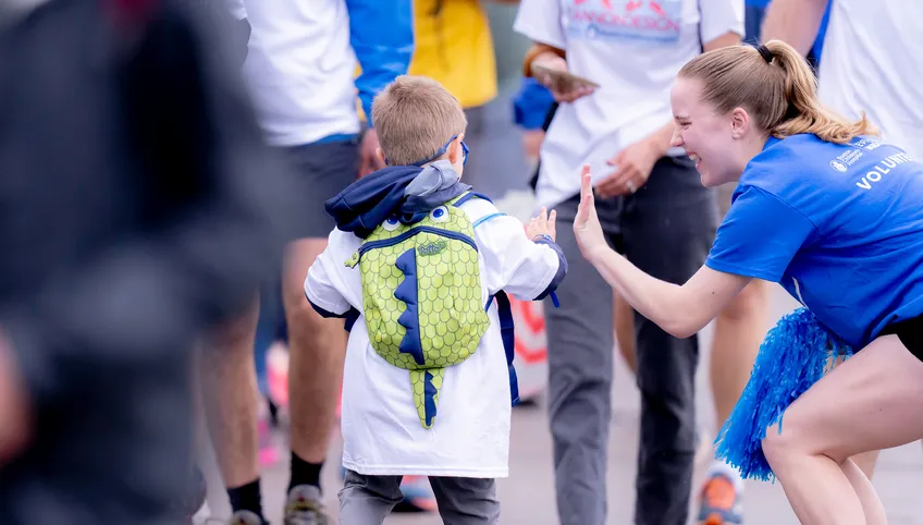 An Eversource Walk volunteer high fives a young boy participating in the event