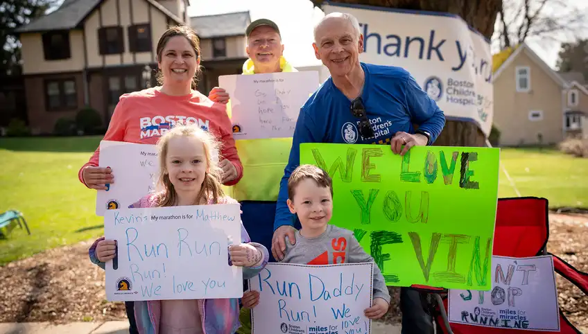 A smiling family stands holding signs that read "thank you"