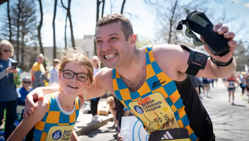 A marathon runner poses with a young BCH patient