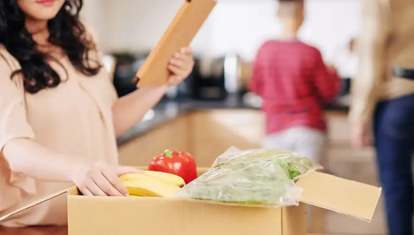 A woman packs a box full of food