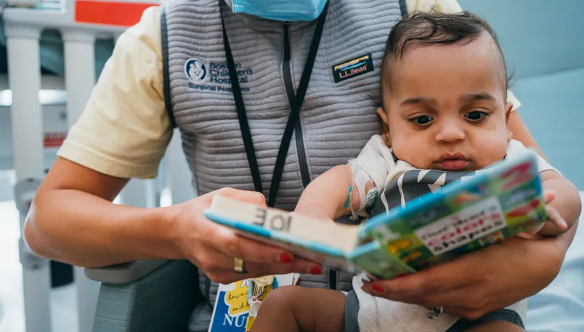 a child with a book as a caregiver reads to them