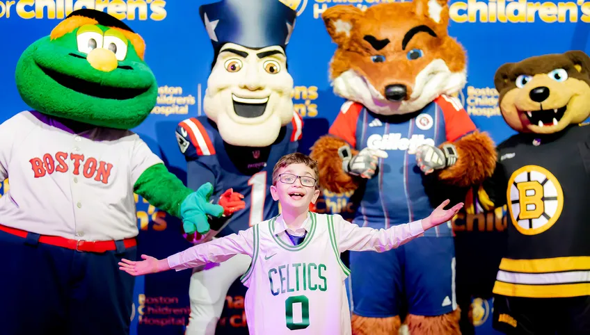 boy in glasses wearing a Celtics jersey in front of mascots