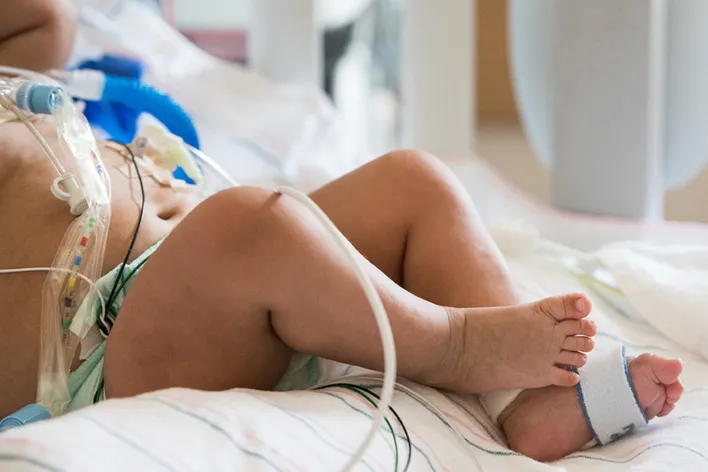 A closeup shot of a baby's feet who is hooked up to a respirator.