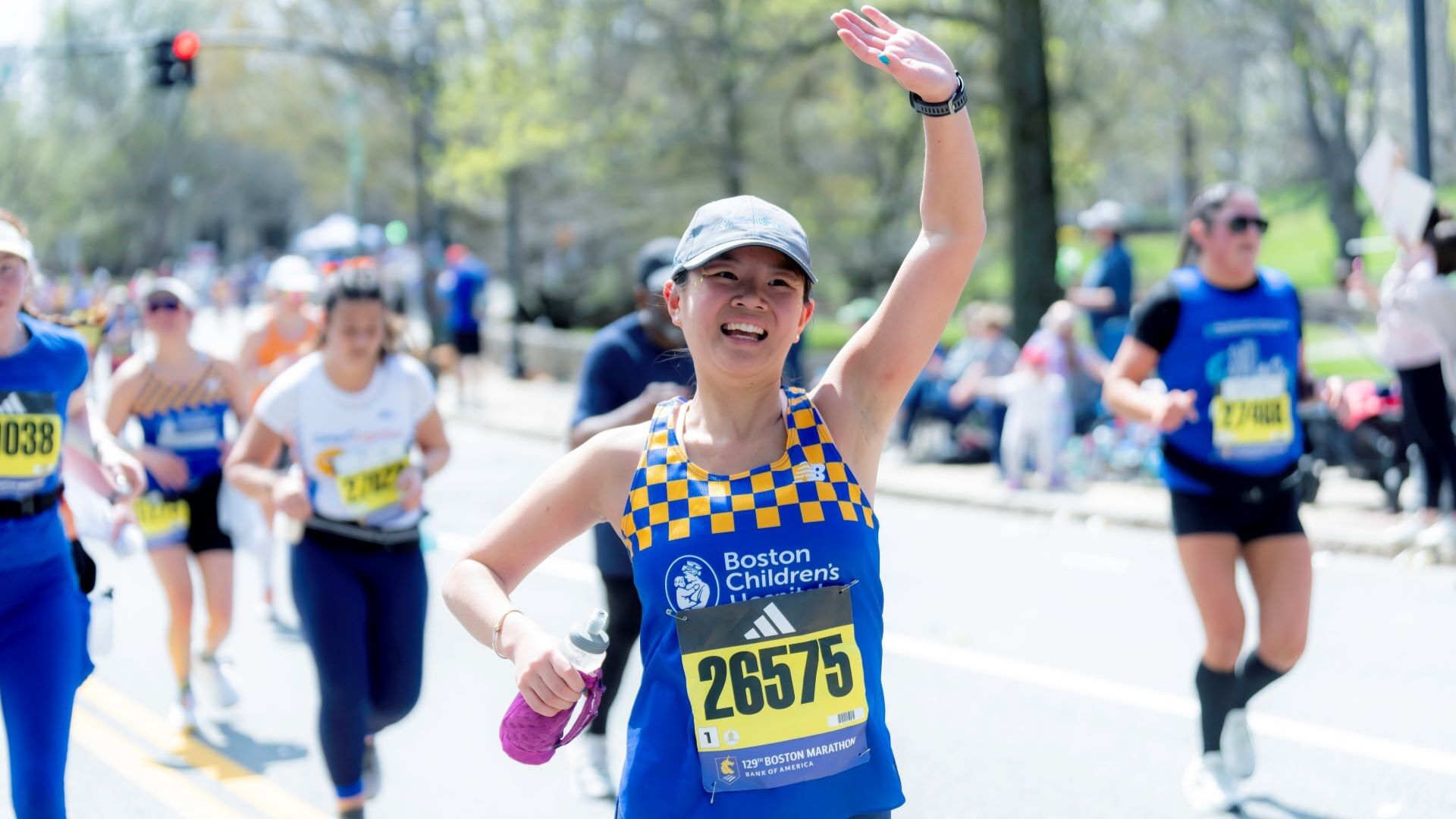 woman running marathon waving at crowd