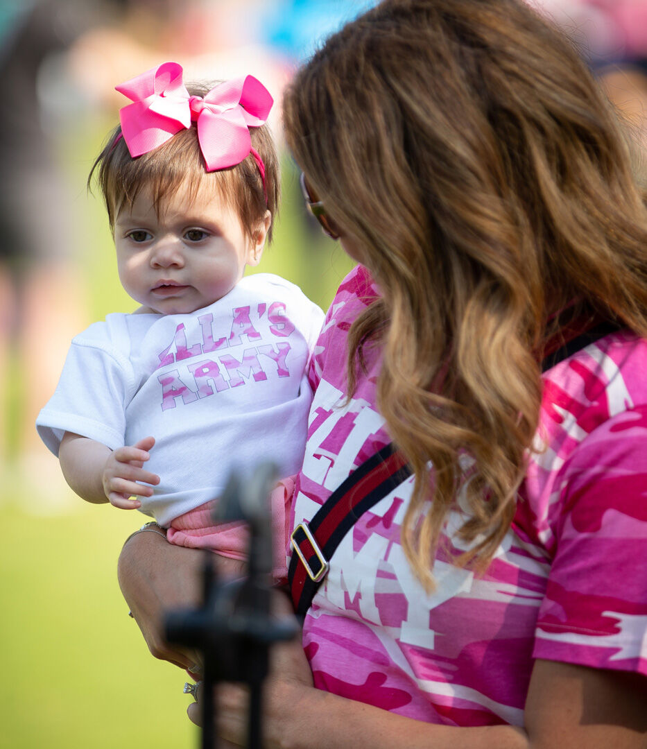 Mother wearing pink tshirt holding baby girl with pink bow in her hair
