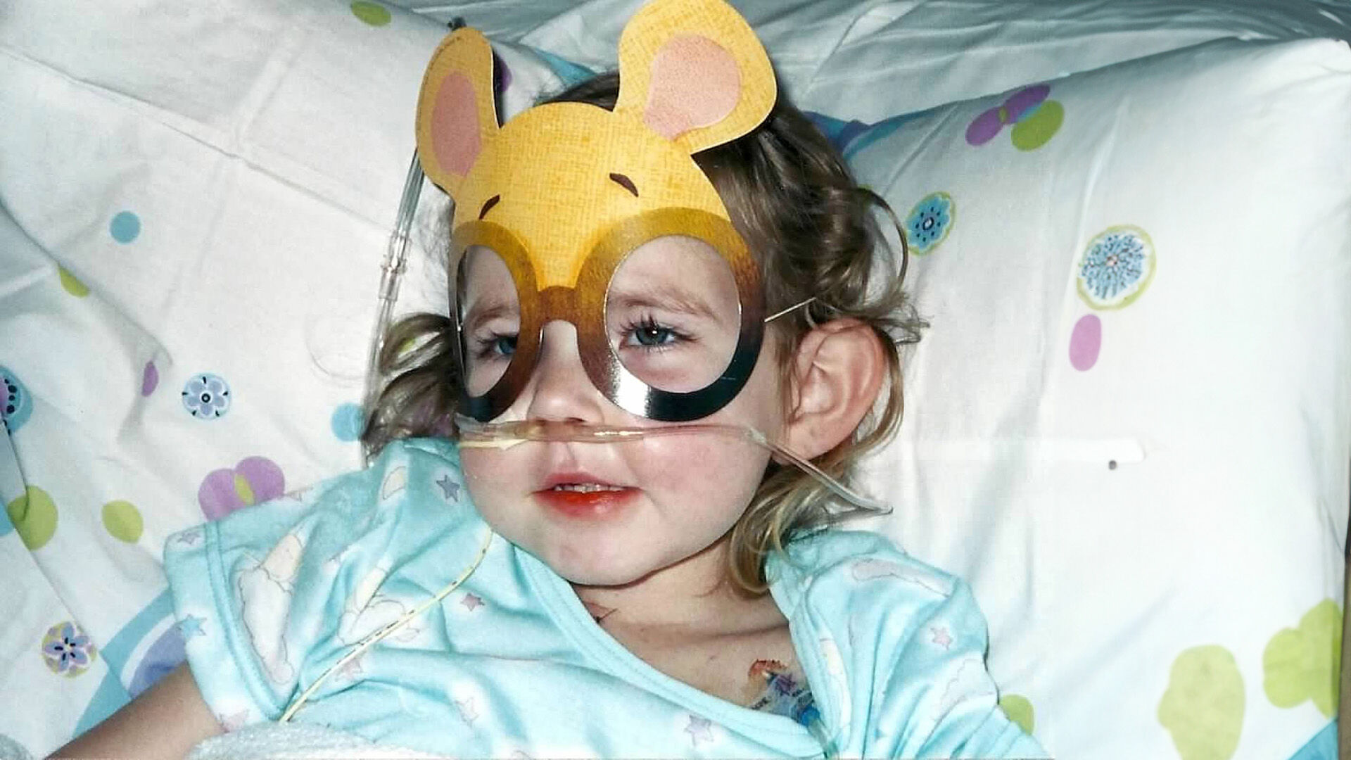little girl with mask on lying in a bed