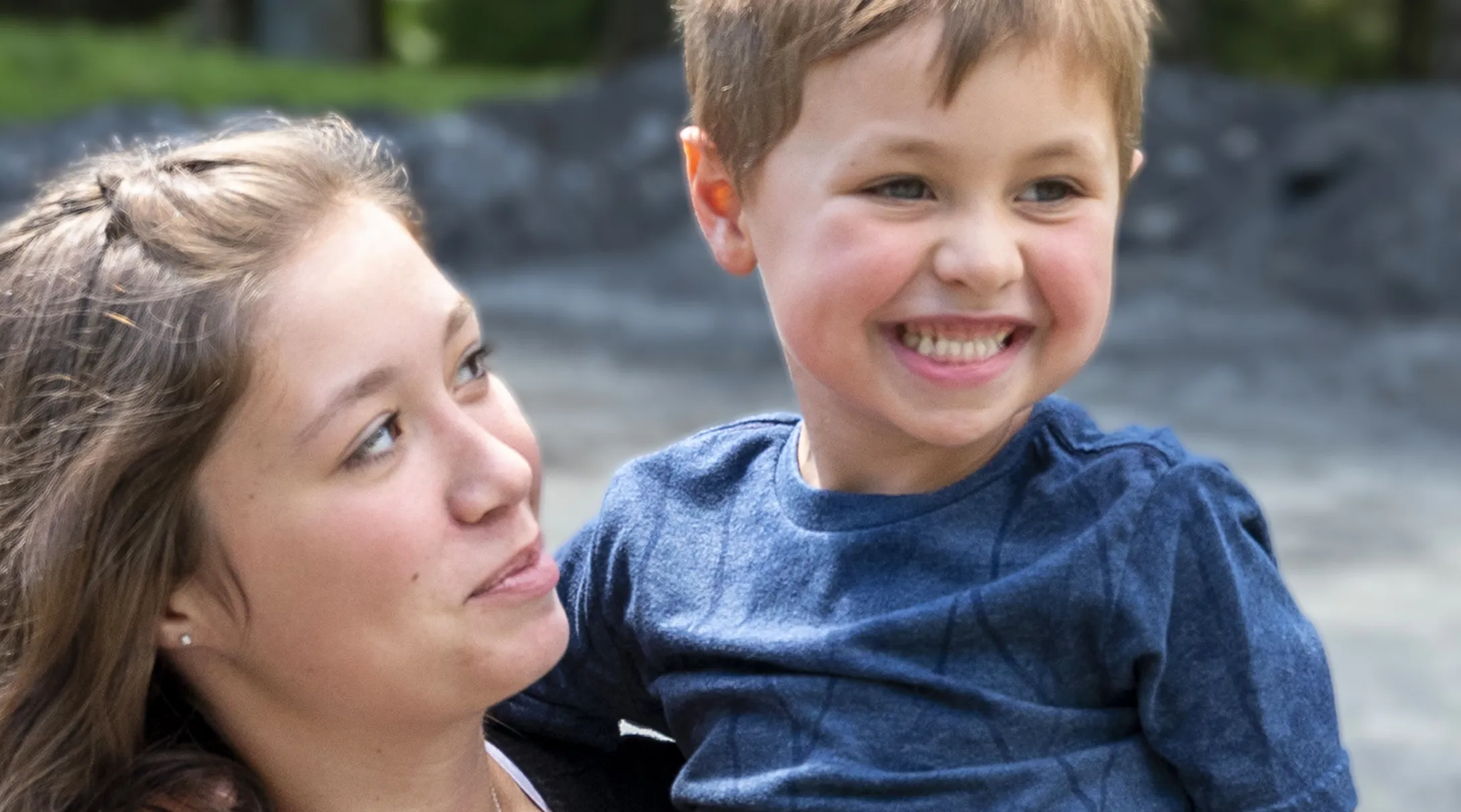 A young boy, Presley, being held by his mom with a big smile on his face
