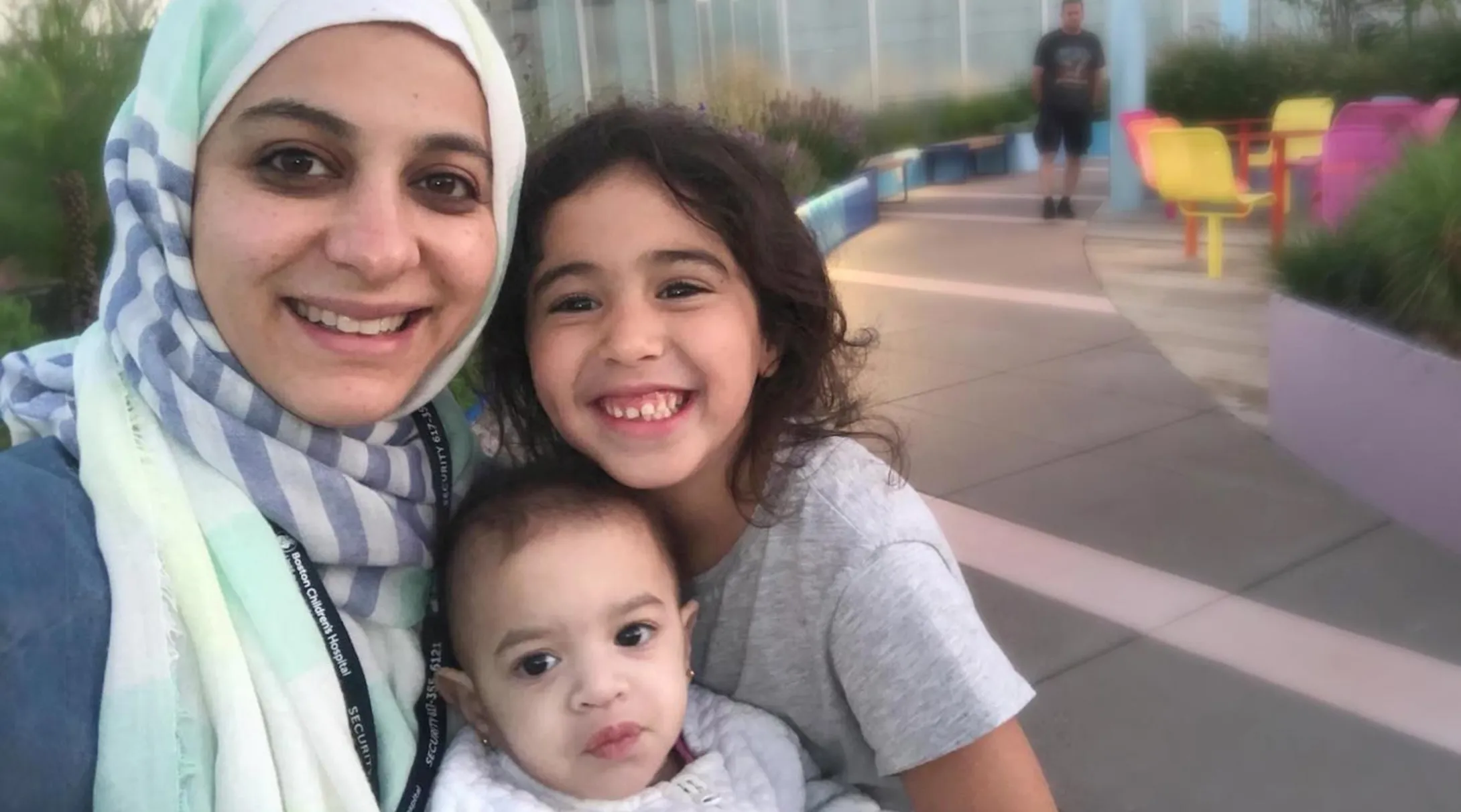 A mother smiles with her two children, including BCH patient Laila