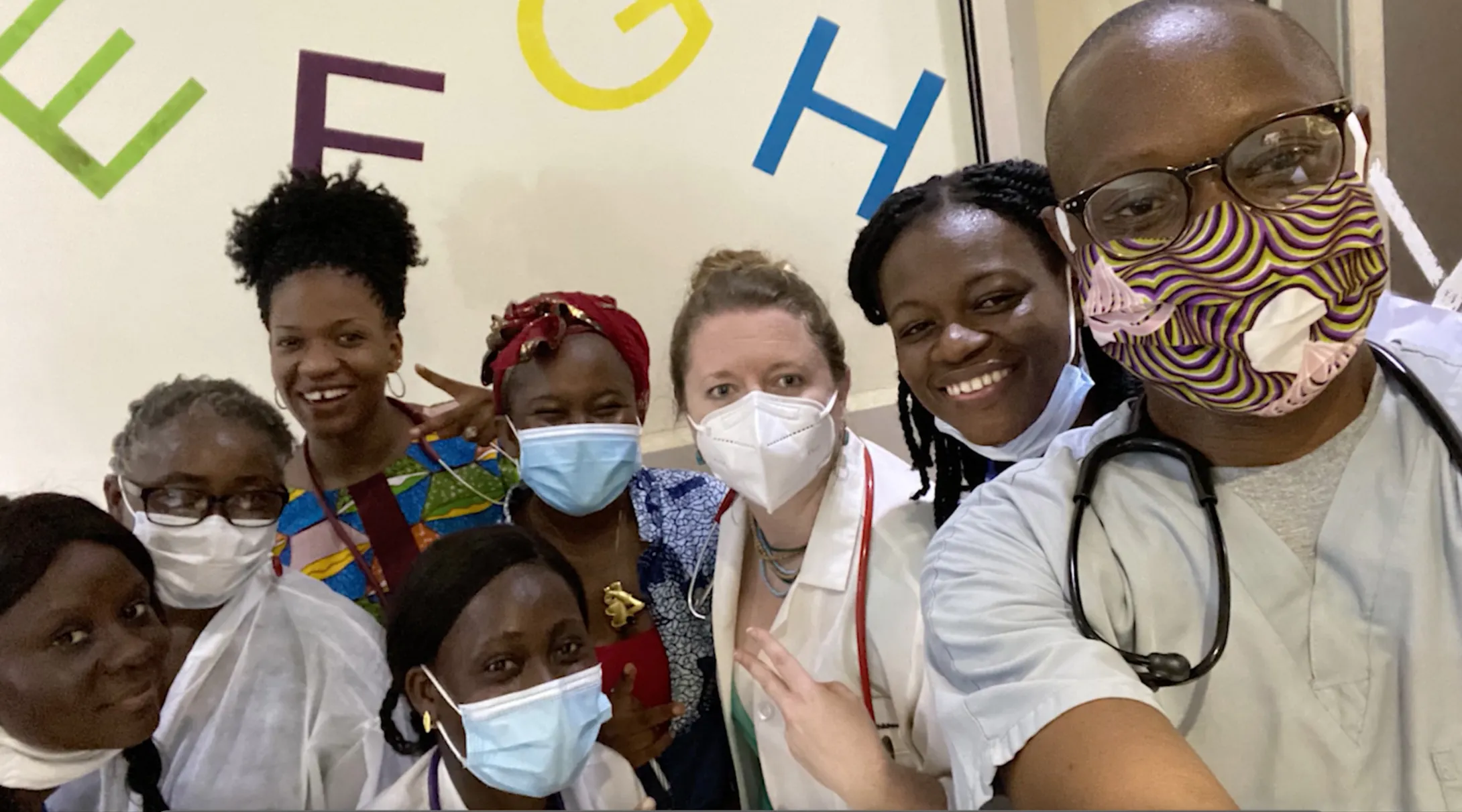 A group of children and doctors wearing medical masks smiling at the camera