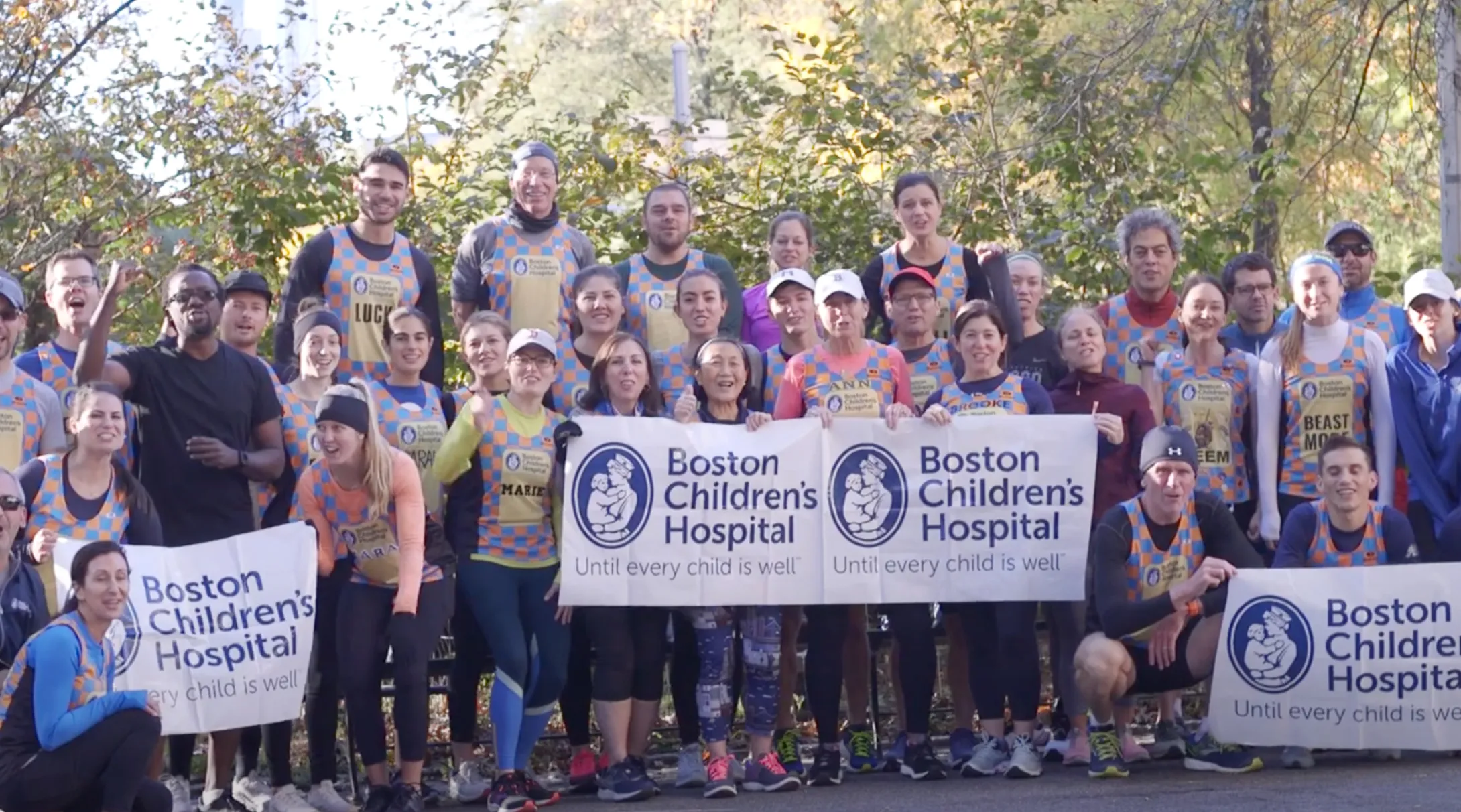 Group of people cheering on runners holding Boston Children's Hospital banners