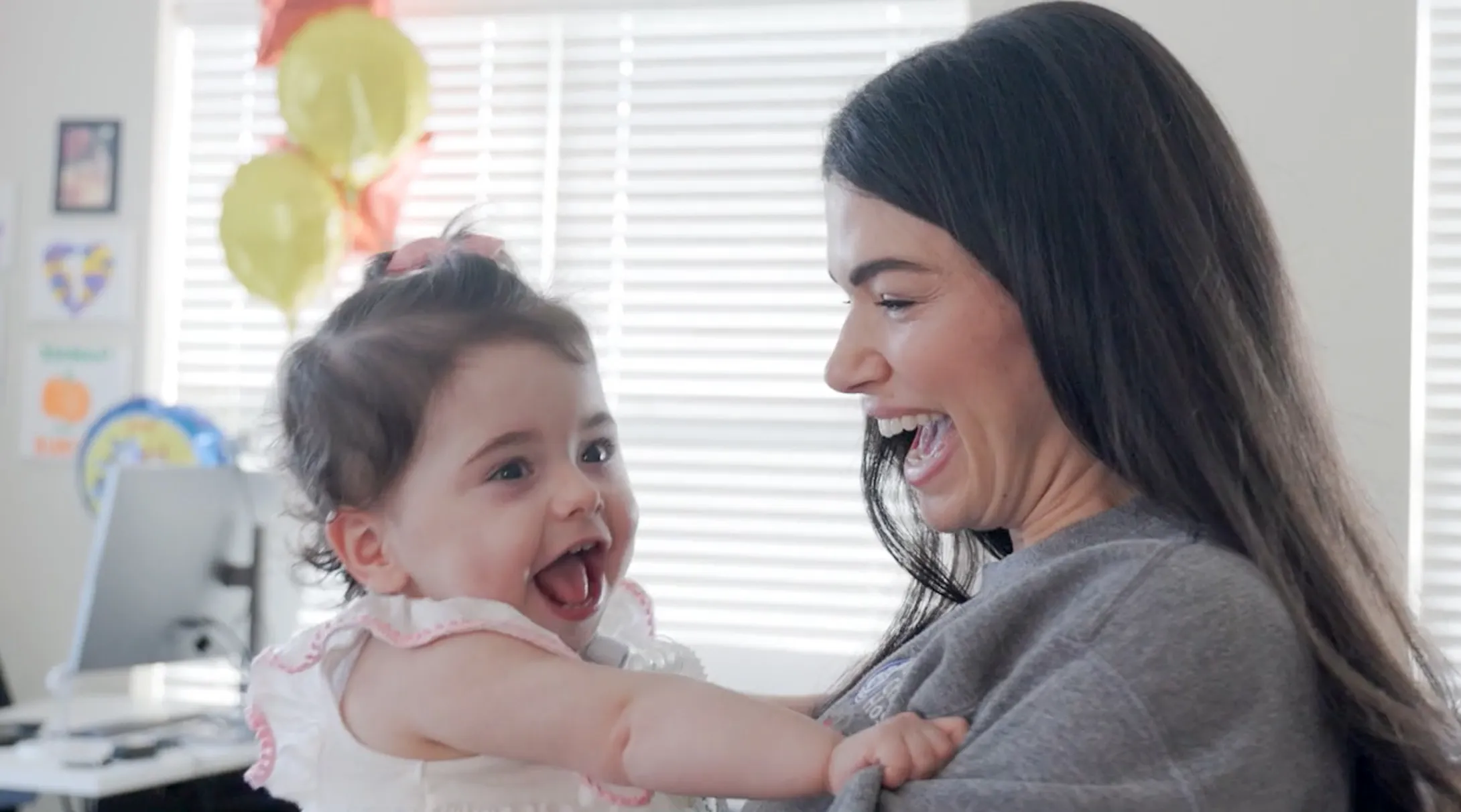 mother holding smiling young baby daughter