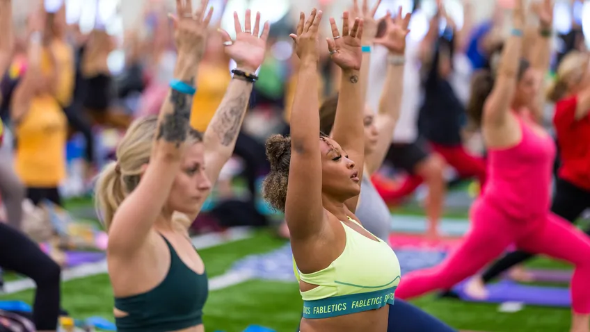 A group of Yoga Reaches Out participants reach their arms in the air in Warrior One pose