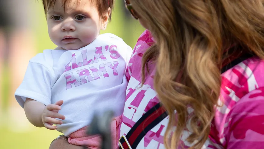 Mother wearing pink tshirt holding baby girl with pink bow in her hair