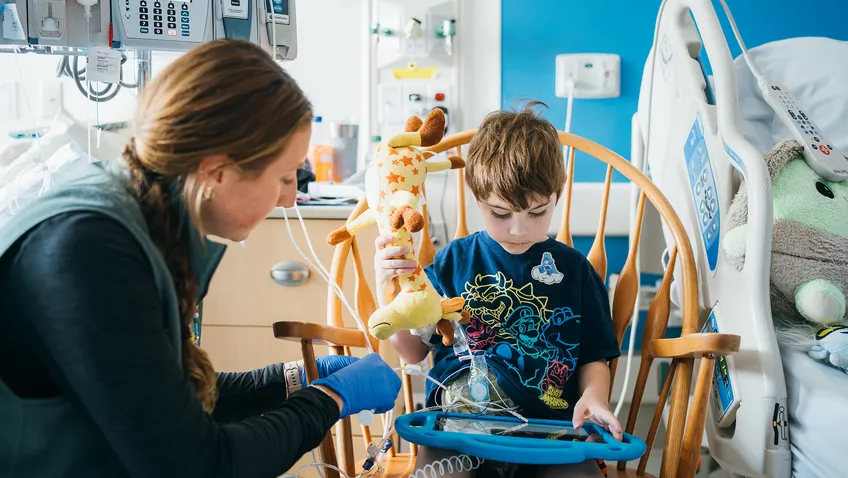 young boy in his hospital room, playing with nurse next to him