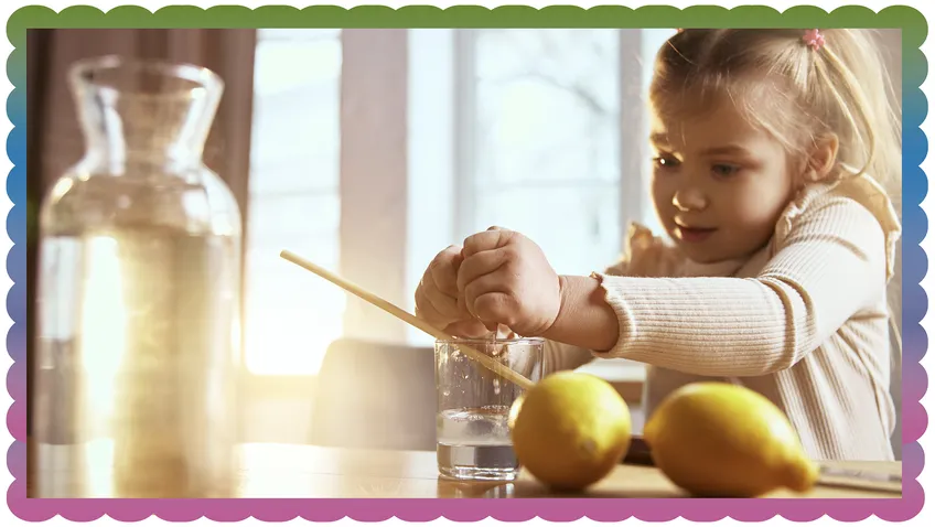 child squeezing a lemon into a cup