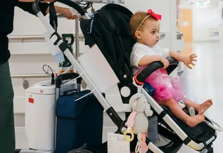 A BCH patient, Avianna, in a stroller hooked up to a complex piece of medical equipment