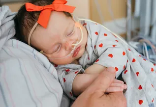 Kalea with a breathing tube being held by her mother