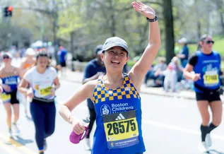 woman running marathon waving at crowd