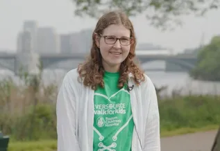 girl with glasses in green shirt standing along the Charles River in Boston